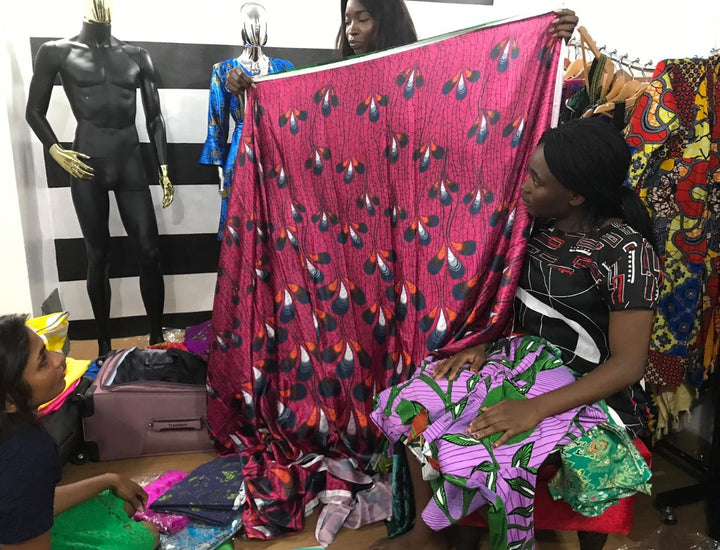 Bolaji, one of our tailors holding up a pink and yellow ankara fabric