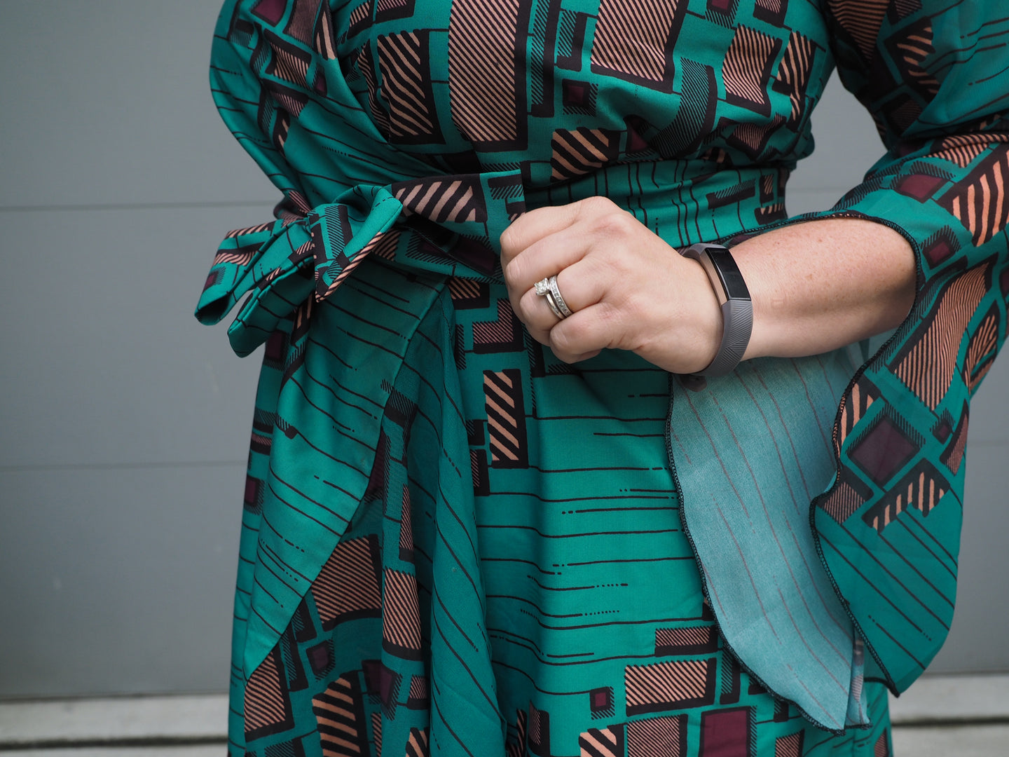 A close-up of a green Katie Keynote maxi wrap-dress in a green print with purply accents